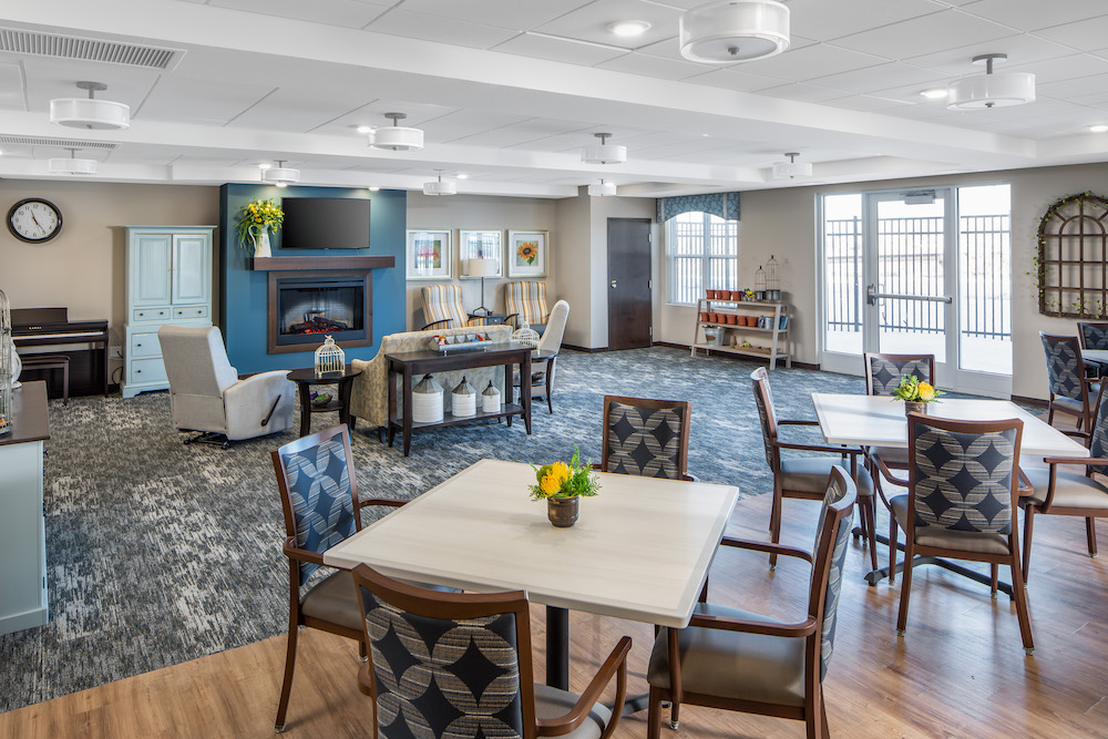 Bright and spacious communal room with comfortable seating, tables, and a fireplace.