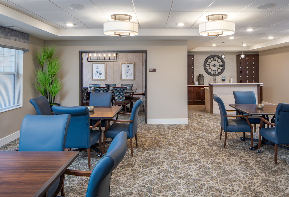 Modern communal dining area with blue chairs, wooden tables, and wall art in the background.