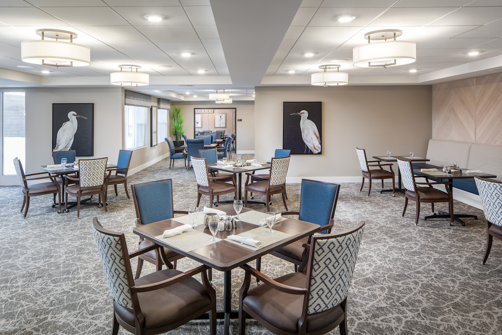 A modern dining area with elegant furnishings and bird-themed artwork on the walls