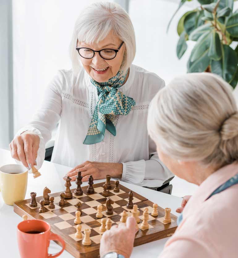seniors-playing-chess Two senior women playing chess together at a table, enjoying each others company.