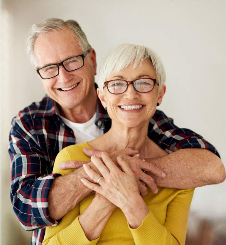 senior-couple Smiling senior couple embracing indoors, wearing glasses and casual clothing.