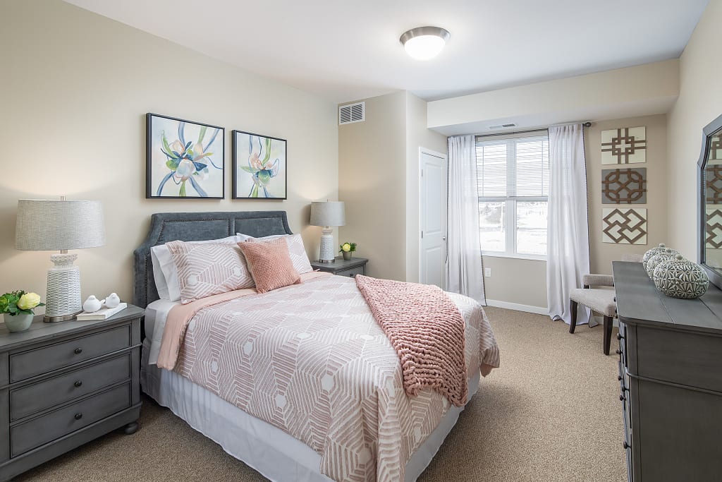 Decorated bedroom with bedside tables, a dresser, and chair.